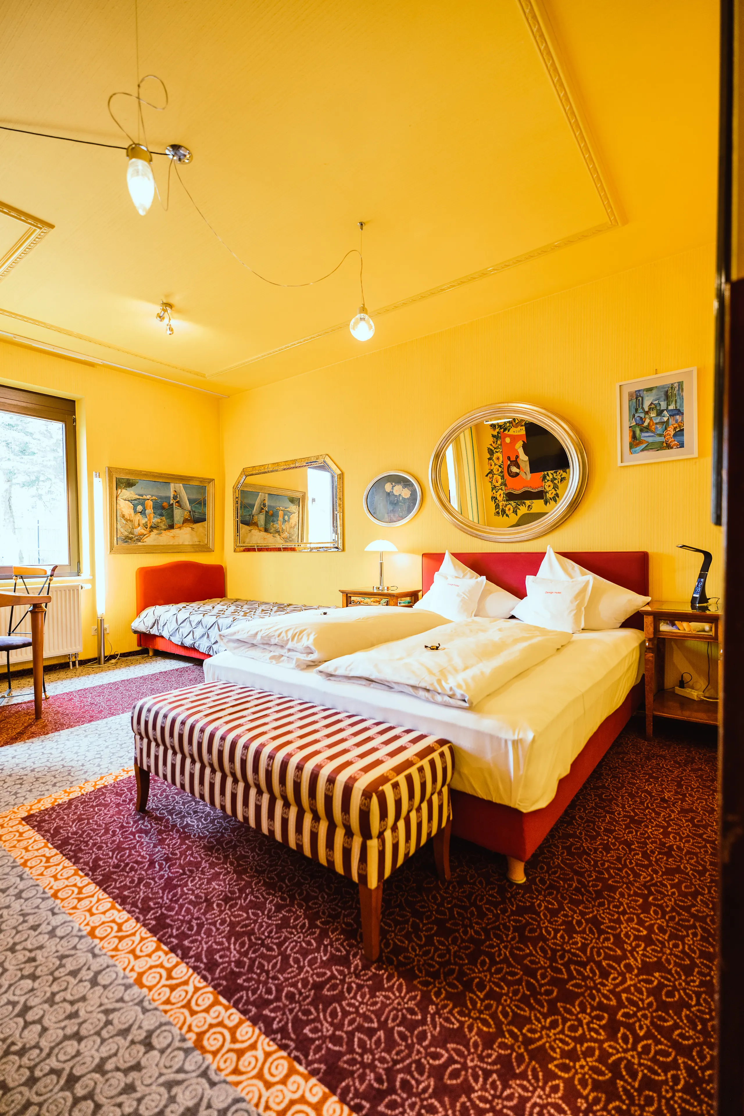 “Relax” themed room in yellow, featuring a bed, framed paintings, and a patterned rug.